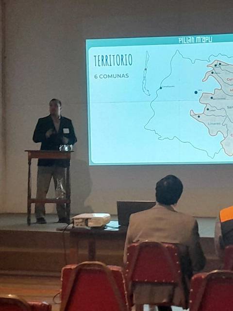 Un presentador expone sobre un mapa en un evento académico.