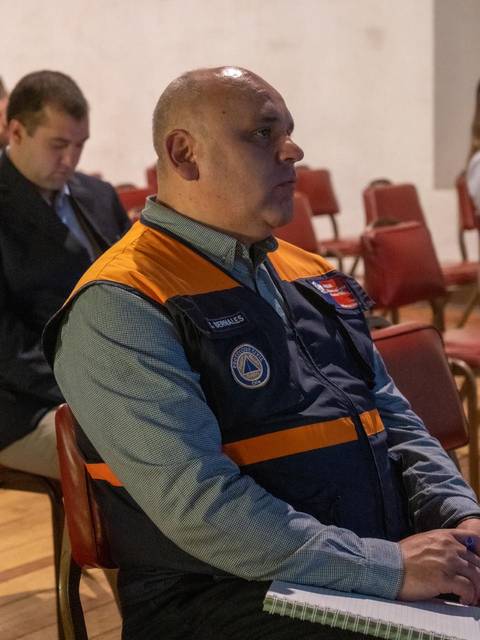 Un hombre sentado en una silla escucha atentamente en un encuentro.