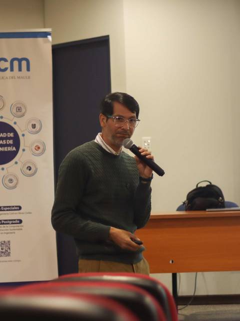 Un hombre está dando una presentación frente a una audiencia en un salón de conferencias.