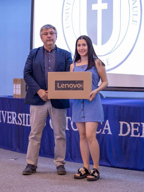 Un hombre y una mujer posan juntos en un evento académico mientras ella sostiene una caja de Lenovo.