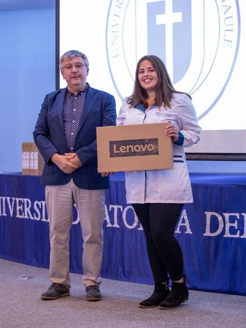 Una estudiante recibe un premio de un profesor en una ceremonia en la universidad.