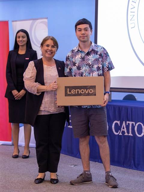 Un grupo de personas en un evento, con un hombre sosteniendo una caja de Lenovo y dos mujeres de pie detrás.