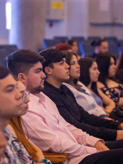 Un grupo de personas sentadas en un auditorio prestando atención a un evento.