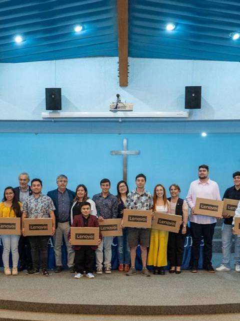 Un grupo de personas sonrientes sostiene cajas en un evento realizado en un auditorio.