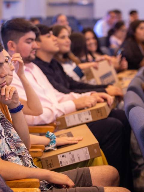Un grupo de personas sentadas en un auditorio durante un evento.