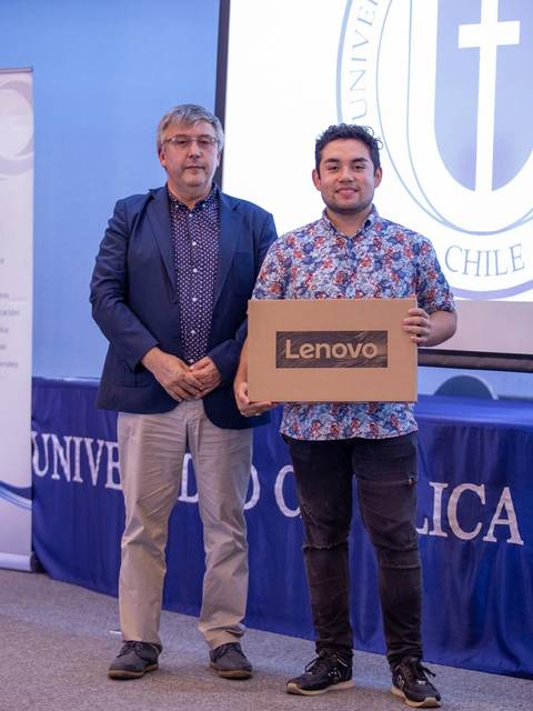 Dos hombres posan con una caja de un producto Lenovo en un evento universitario.