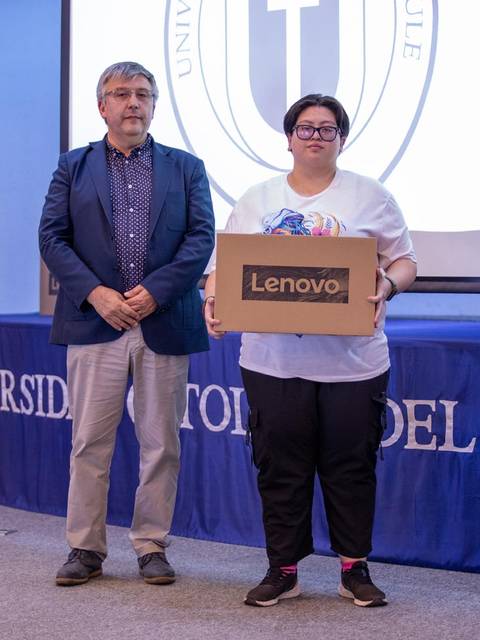 Una mujer sostiene una caja de un producto Lenovo mientras está junto a un hombre en un evento en la universidad.