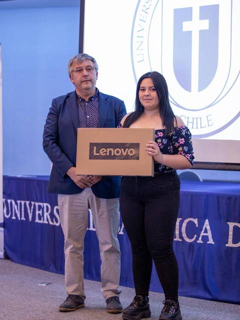 Una estudiante recibe un premio de una computadora Lenovo durante un evento en la universidad.