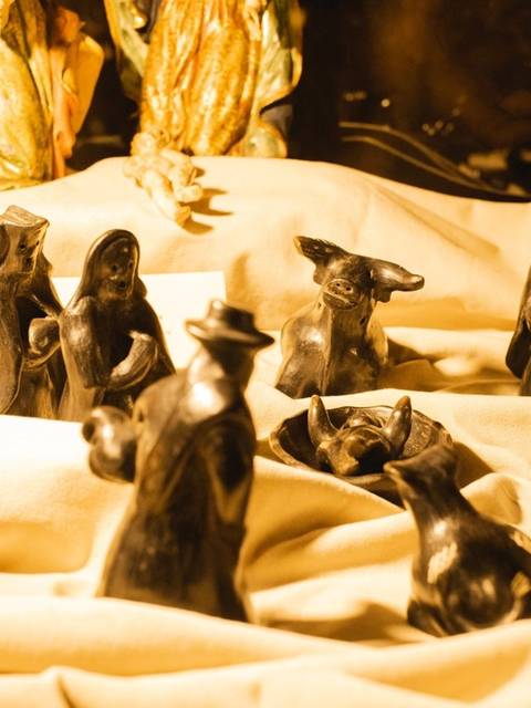 Una colección de figuras de arcilla negra dispuestas sobre una tela clara.