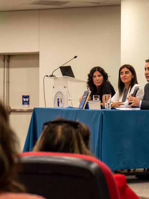 Una mesa redonda con tres ponentes discutiendo en un auditorio.
