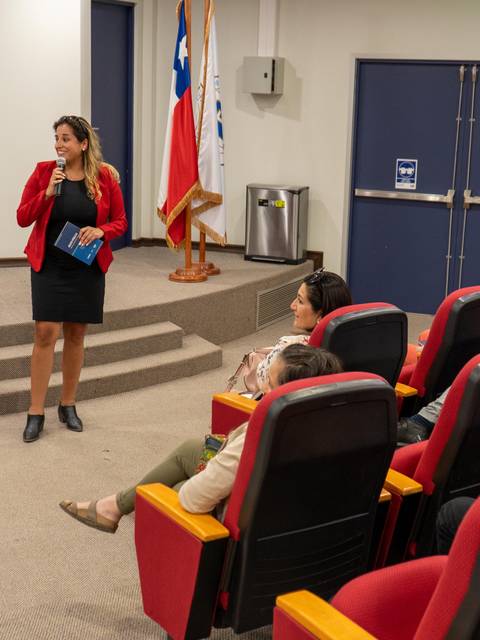 Una mujer que presenta en un auditorio mientras un grupo de personas la observa atentamente.