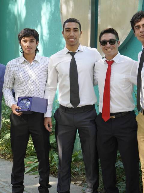 Un grupo de cinco jóvenes posando juntos sonrientes en un ambiente al aire libre.
