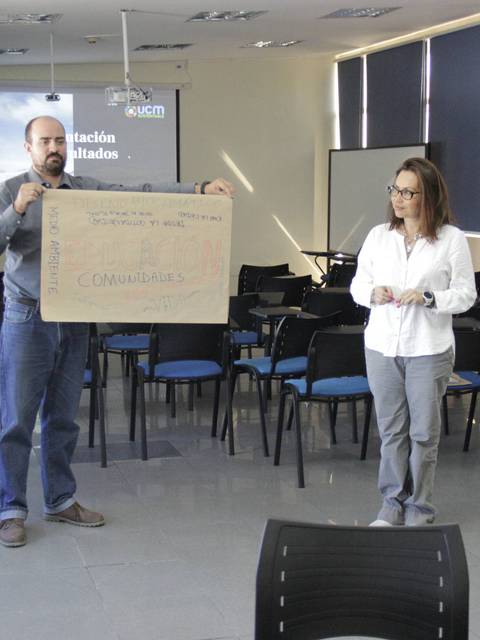 Un grupo de tres personas presenta un cartel en un evento sobre sostenibilidad.