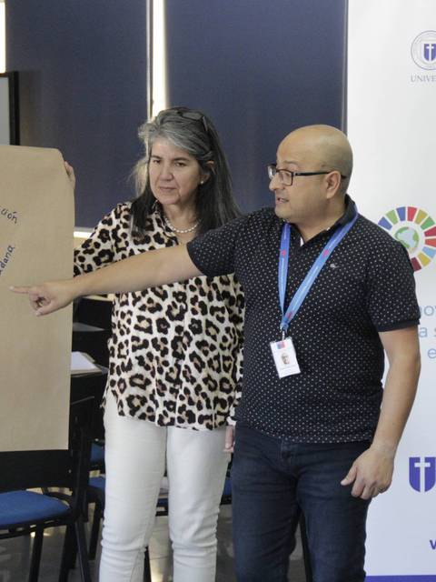 Un grupo de personas presenta un cartel con palabras clave sobre un tema educativo en un entorno académico.