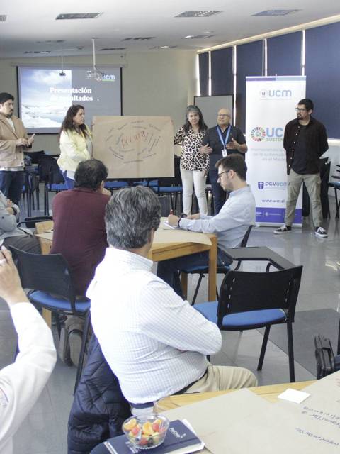 Un grupo de personas interactúa en una sala de conferencias durante una presentación.