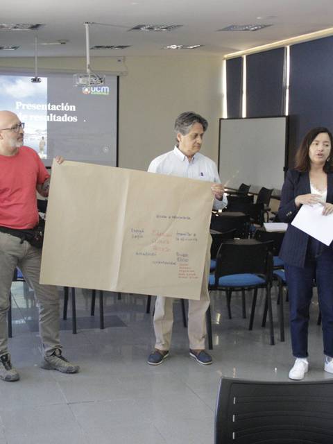 Un grupo de personas presenta un proyecto en un salón de clases utilizado para conferencias.