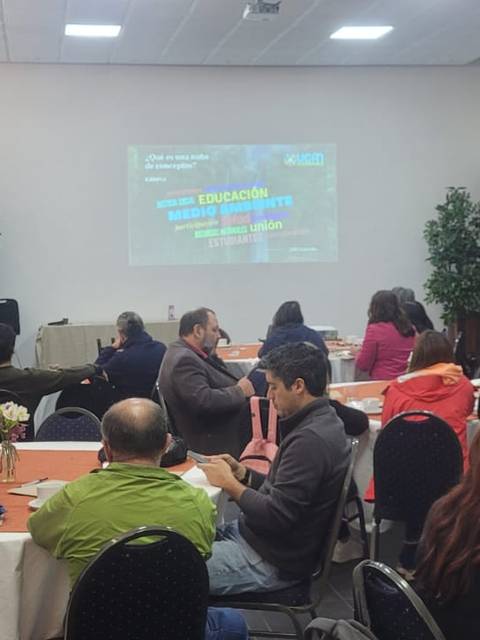 Una sala de conferencias con un gran grupo de personas atendiendo a una presentación.