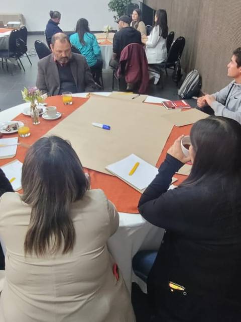 Un grupo de personas reunidas en una mesa durante una actividad de trabajo en equipo.