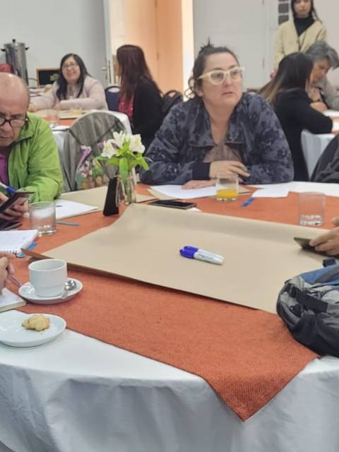 Un grupo de personas discutiendo en una mesa con bocadillos y bebidas a su alrededor.