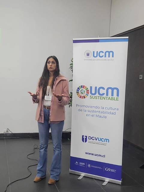 Una mujer está hablando frente a un banner que promueve la sostenibilidad en UCM.