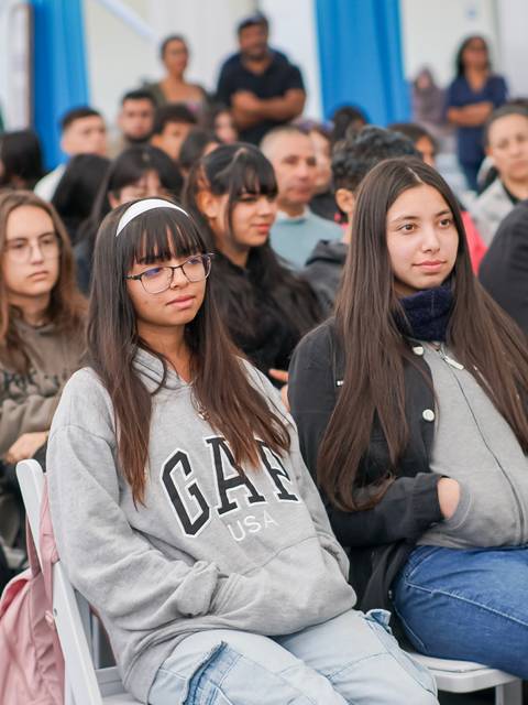 Un grupo de jóvenes sentados en un evento, mostrando diversas expresiones y estilos de vestir.