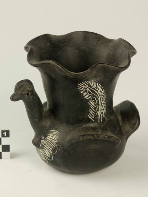 Una jarra de cerámica negra con forma de ave y decoraciones en blanco.