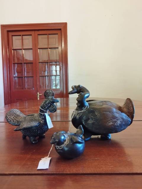Tres figuras decorativas de aves talladas en un material oscuro sobre una mesa de madera.