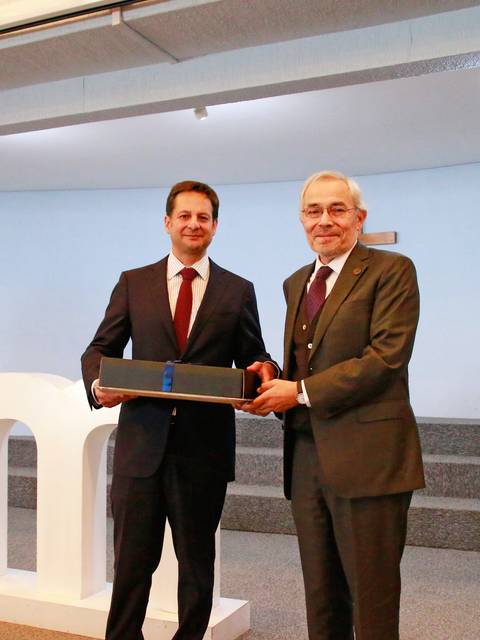 Dos hombres se están dando un regalo en un evento formal.