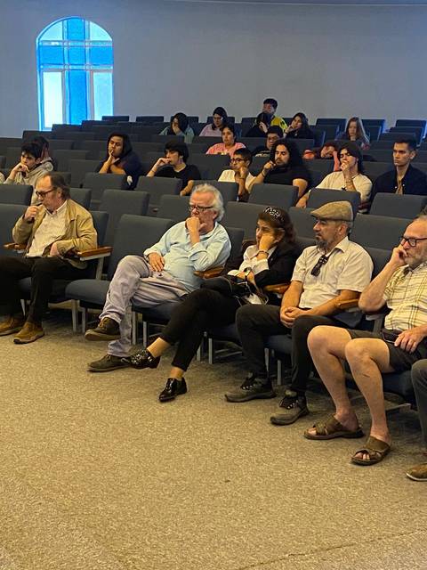 Un grupo de personas sentadas en un auditorio, prestando atención a un evento.