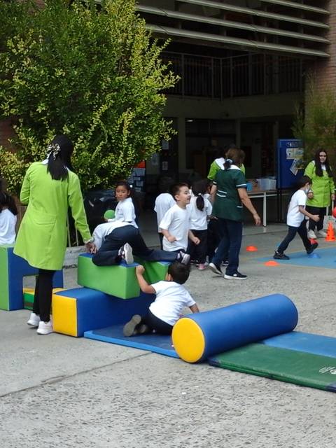Un grupo de niños juega en un área de recreo utilizando diferentes objetos educativos.