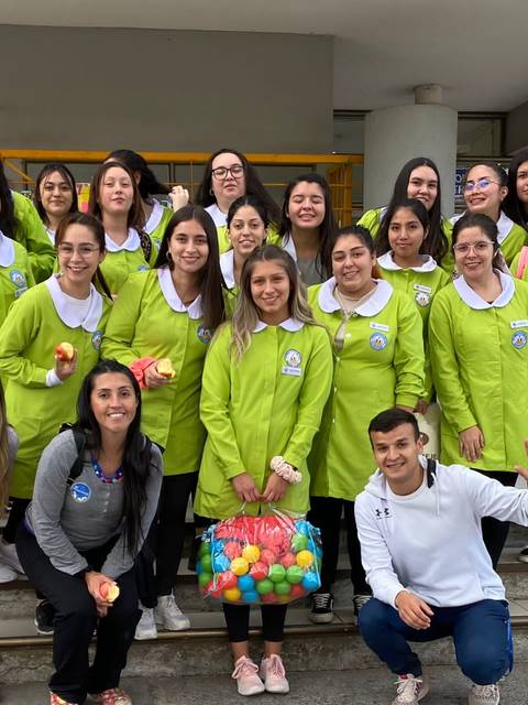 Grupo de personas posando juntas con camisetas verdes y sonriendo en un ambiente al aire libre.