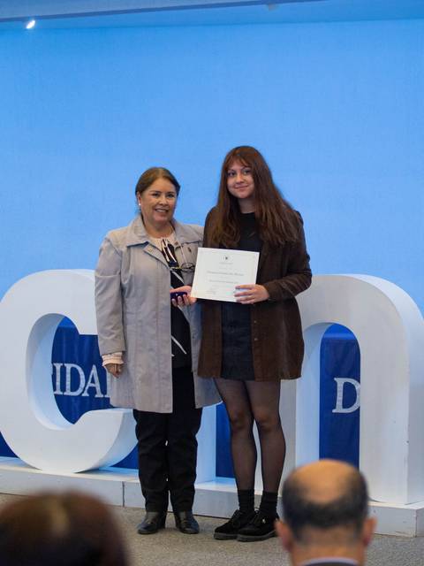Dos mujeres posan con un certificado en un evento de graduación en la UCN.