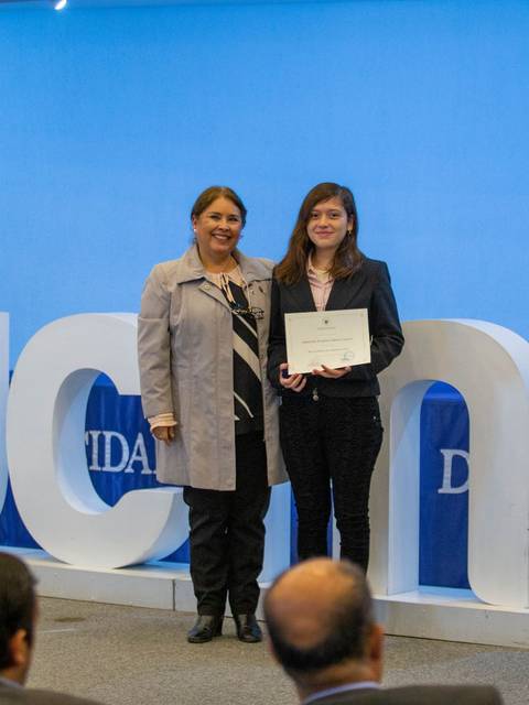 Una ceremonia de entrega de certificados con personas posando ante un fondo decorado.