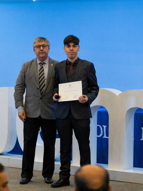 Un estudiante recibe un premio en una ceremonia formal.