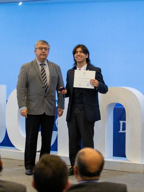 Una ceremonia de entrega de certificados en un evento formal con dos personas en el escenario.