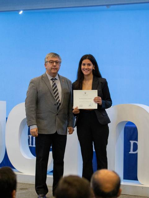 Una mujer y un hombre posan juntos con un certificado en un evento formal.