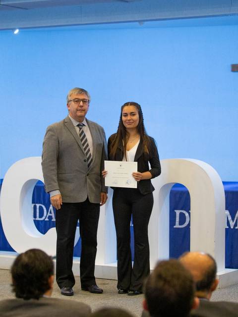 Una ceremonia de entrega de certificados en la UCN con un hombre y una mujer posando para la foto.