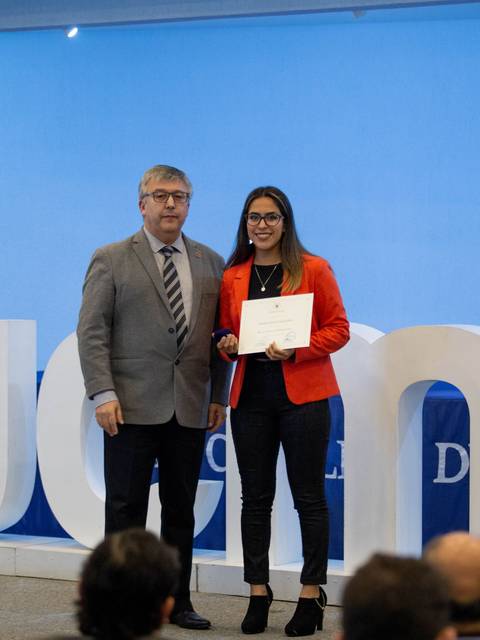 Una mujer recibe un certificado de un hombre en un evento de graduación.