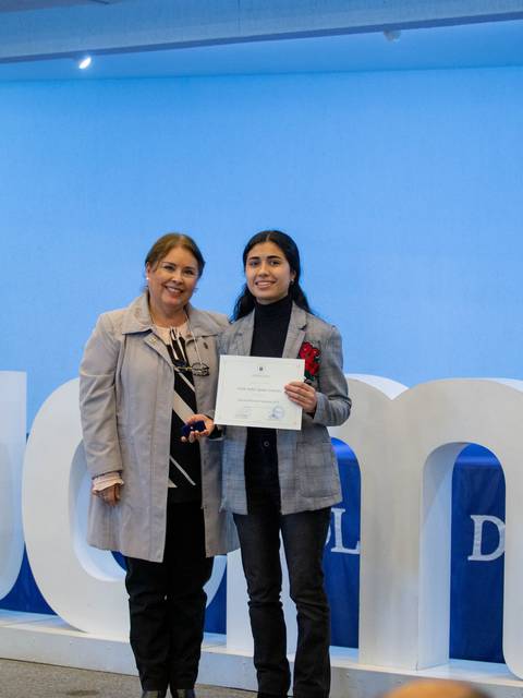 Una joven recibe un certificado de manos de una mujer en un evento de premiación.