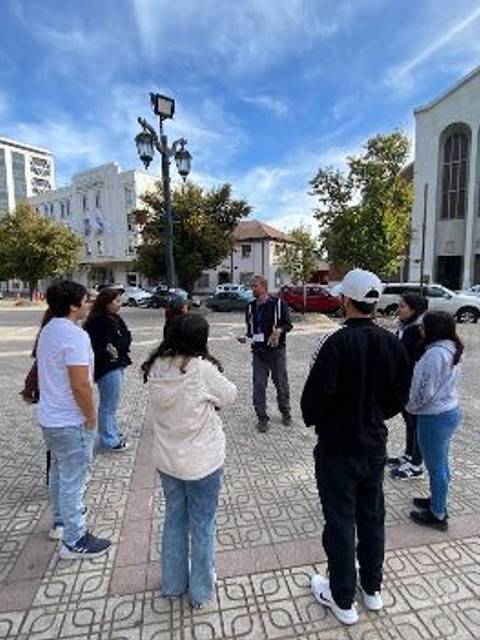 Un grupo de personas se reúne en una plaza mientras un hombre les habla.