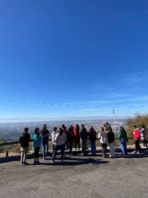 Un grupo de personas observa el paisaje desde un mirador en un día soleado.