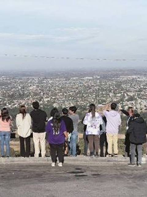 Un grupo de personas observa un paisaje urbano desde una elevación.