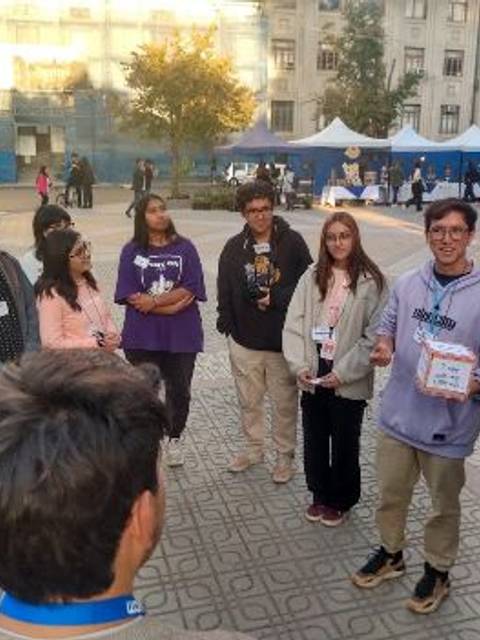Un grupo de jóvenes se reúne en un parque mientras uno de ellos habla frente a los demás.