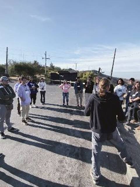 Un grupo de personas se reúne en la calle bajo un cielo despejado.