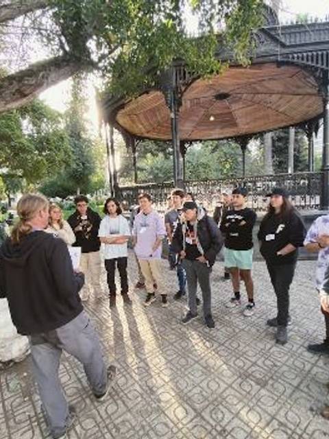 Un grupo de personas se reúne en un parque frente a un quiosco.