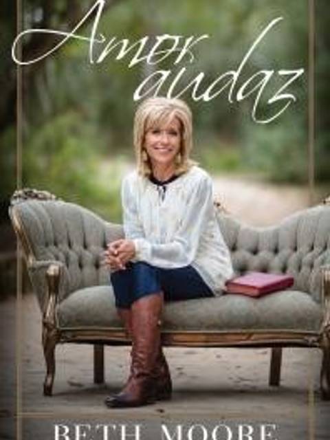 La imagen muestra a una mujer sentada en un sofá con un libro a su lado.