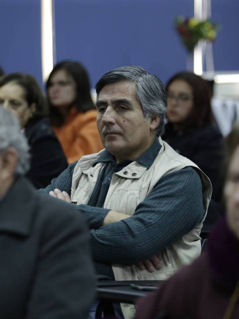 Un grupo de personas sentadas en un auditorio, escuchando atentamente.