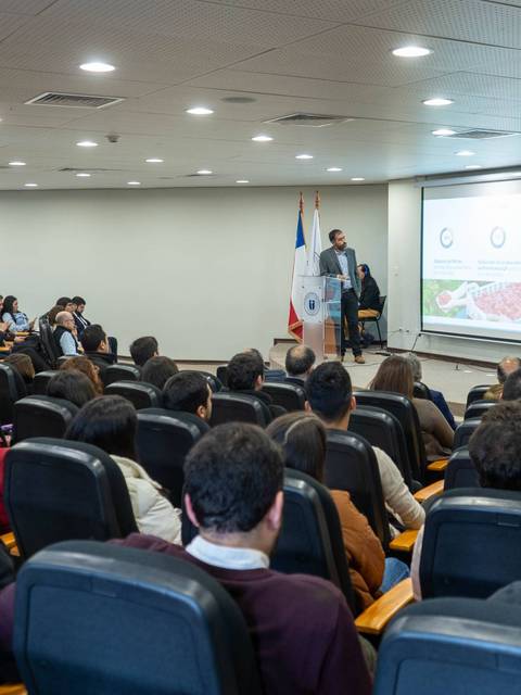Un conferencista presenta ante una audiencia en un salón de conferencias.