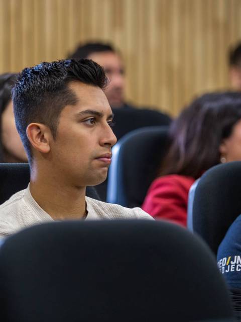 Un grupo de personas está escuchando atentamente en un aula.