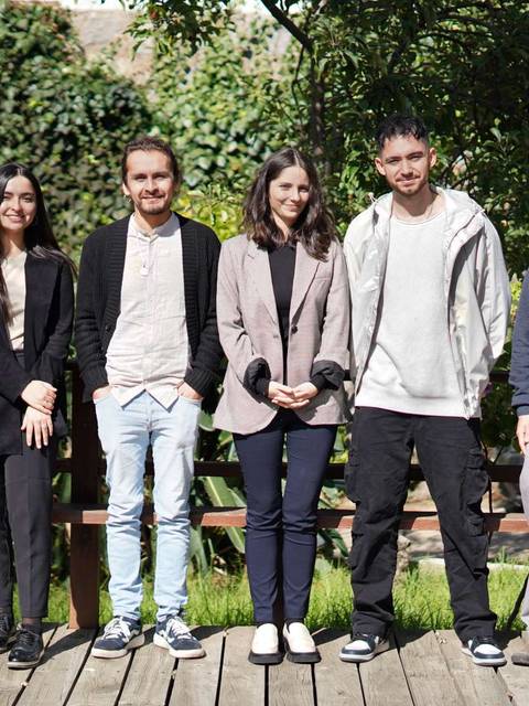 Un grupo de ocho personas posando al aire libre frente a una vegetación verde.